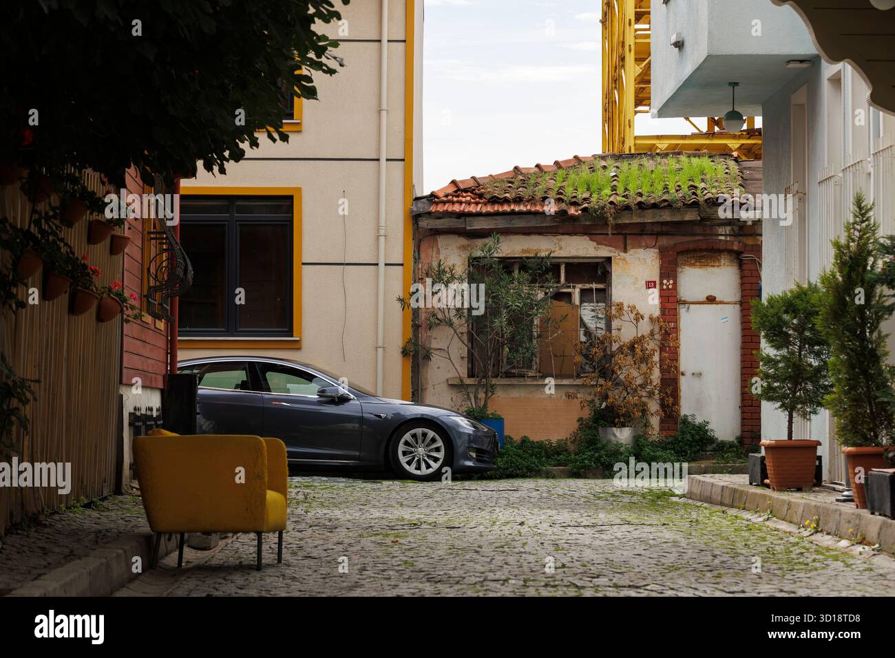 Ein gelber Bus auf der Kopfsteinpflasterstraße und ein graues Auto in der Nähe einer Wohnung in istanbul Stockfoto