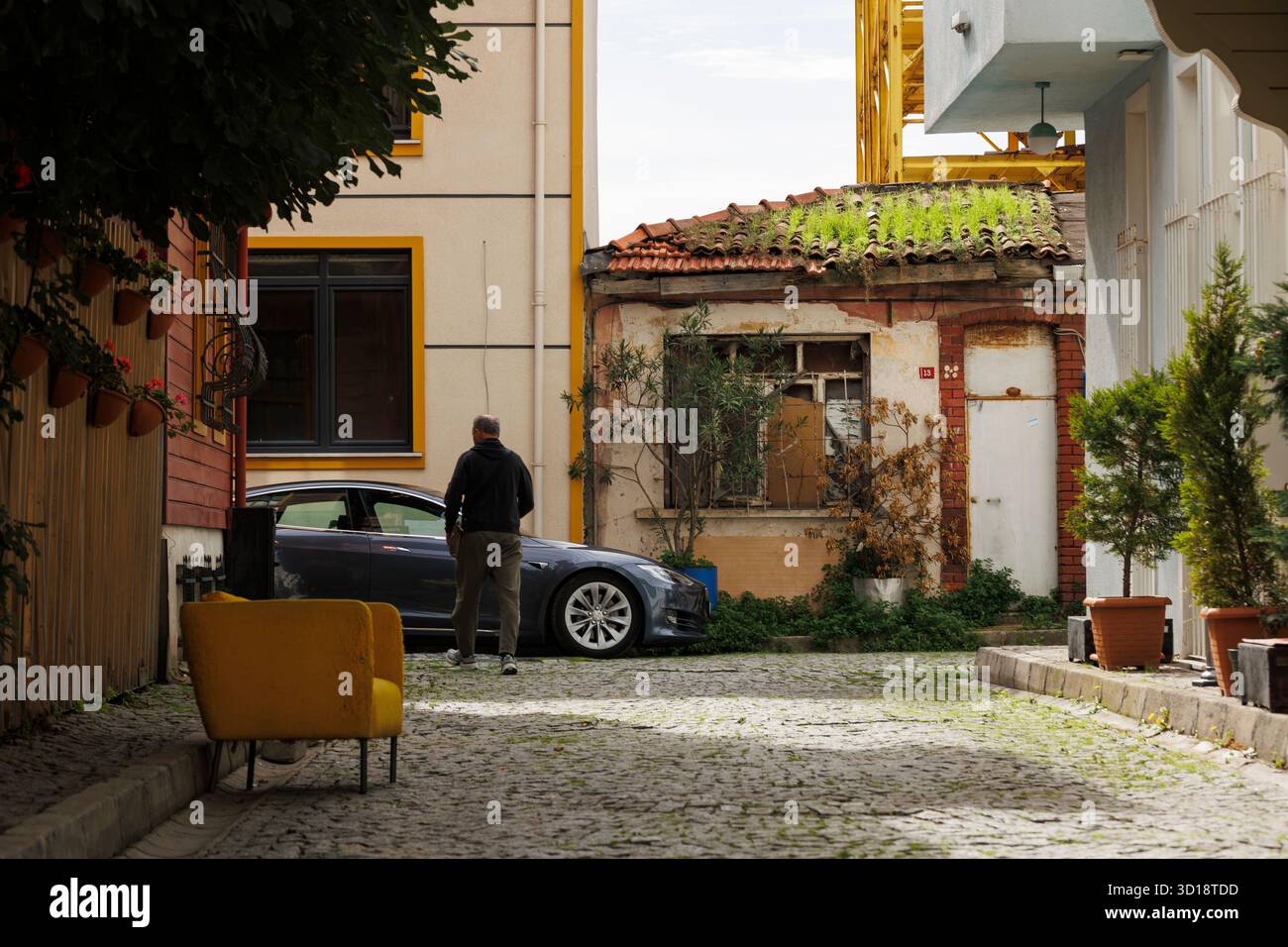 Ein gelber Bus auf der Kopfsteinpflasterstraße und ein Mann fährt in Richtung eines Autos in istanbul Stockfoto