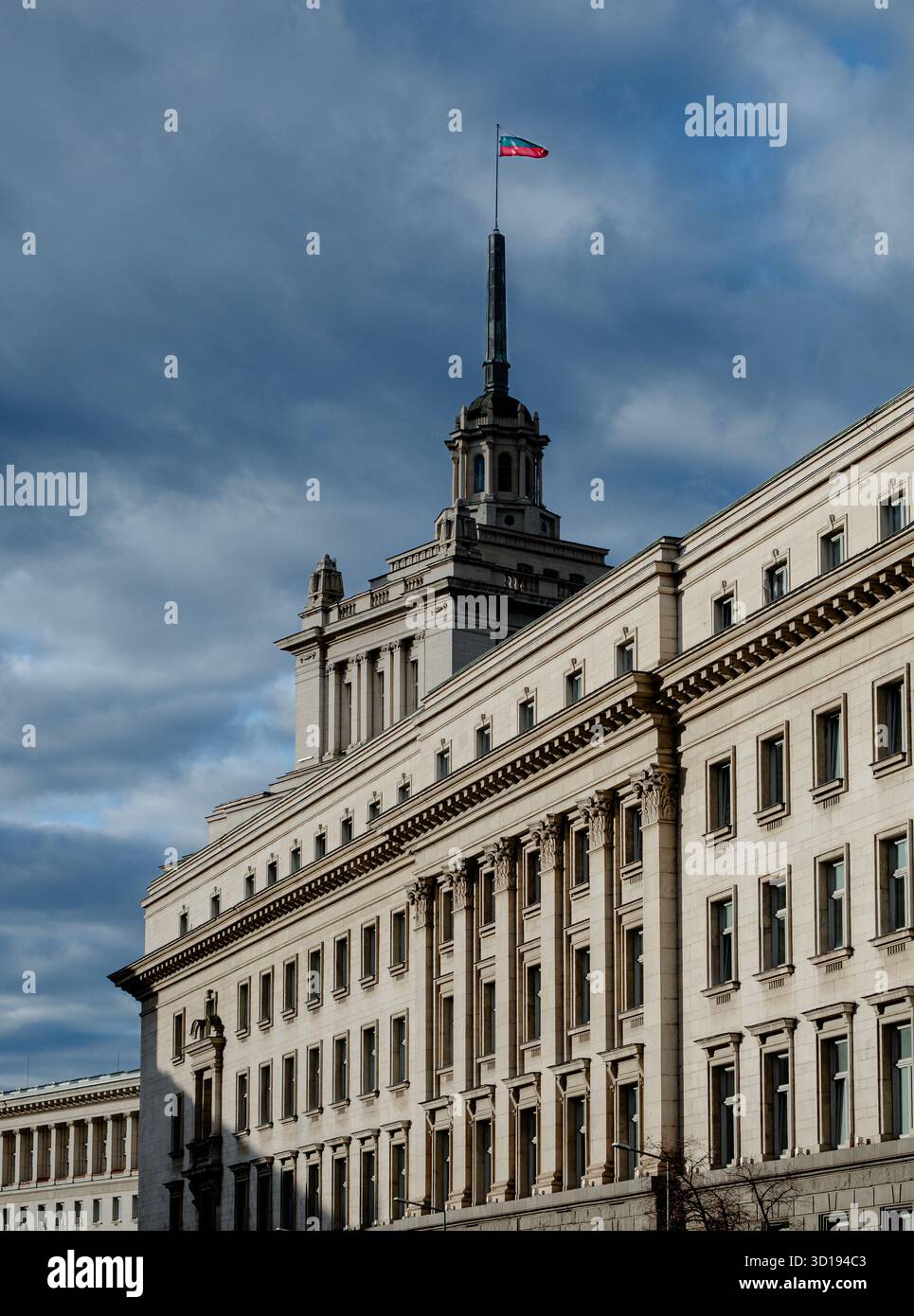 Sofia, Bulgarien - 13. November 2017: Das Gebäude der bulgarischen Nationalversammlung unter einem dramatischen Himmel mit der Nationalflagge auf dem Turm. Stockfoto