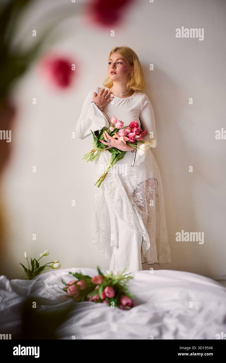 Frau in weißem Kleid mit Blumenstrauß in einer ruhigen Umgebung Stockfoto