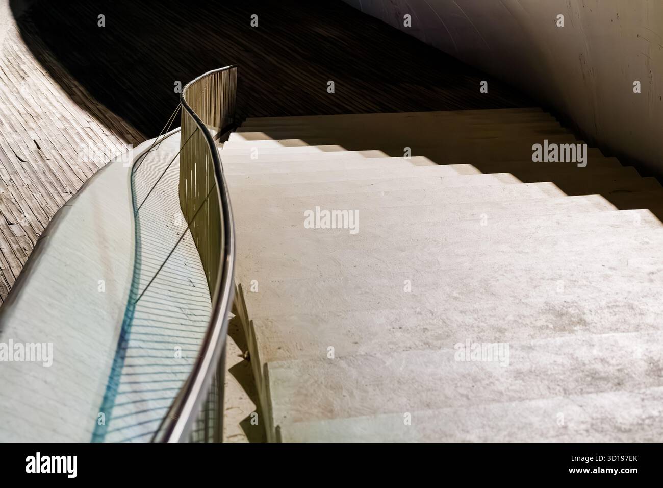 Gebogenes Glas- und Stahlgeländer mit diagonalen Schatten Stockfoto