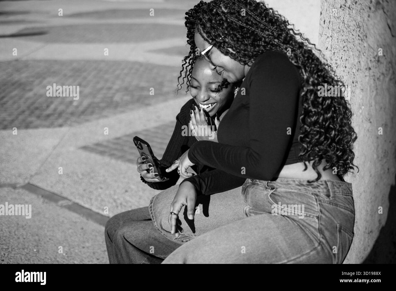 Zwei junge Frauen, die auf ein Telefon schauen Stockfoto