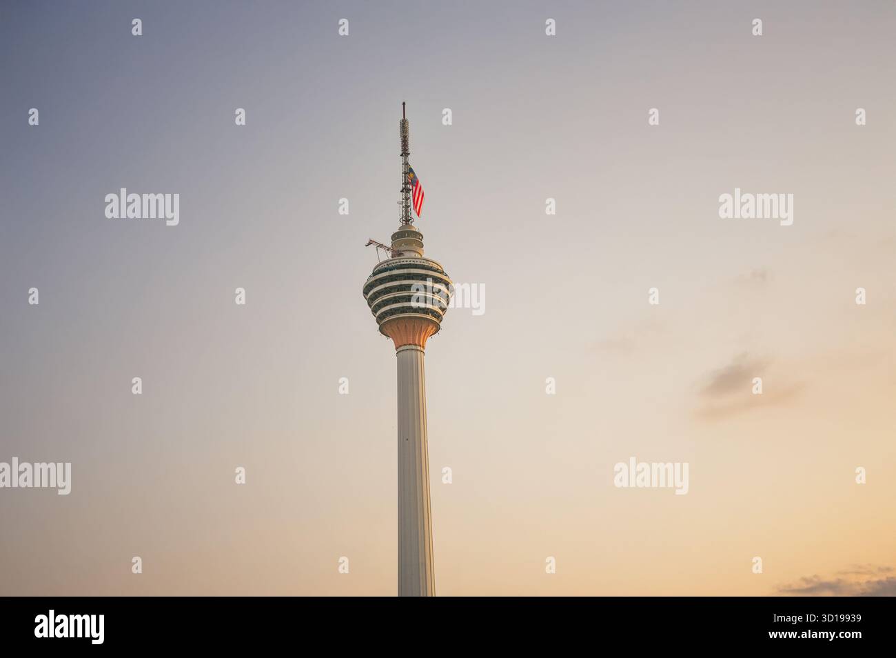 Kuala Lumpur Tower mit malaysischer Flagge bei Sonnenuntergang, Malaysia Stockfoto