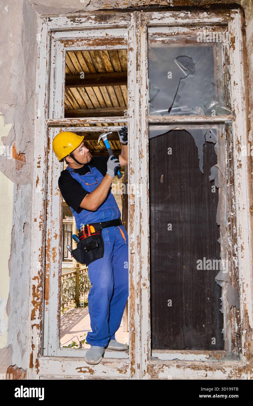 Der Arbeiter repariert das Fenster im alten Gebäude während des Restaurierungsprojekts Stockfoto