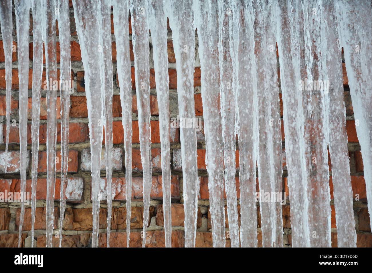 Eiszapfen-Texturhintergrund am kalten, frostigen Wintertag. Das Konzept des Eisdamms. Stockfoto