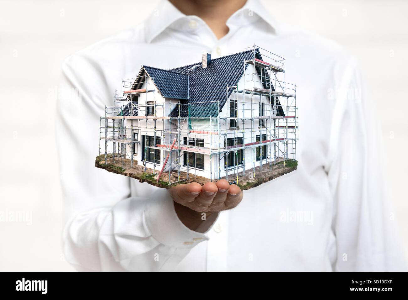 Person, die ein maßstabsgetreues Modell eines im Bau befindlichen Hauses hält Stockfoto