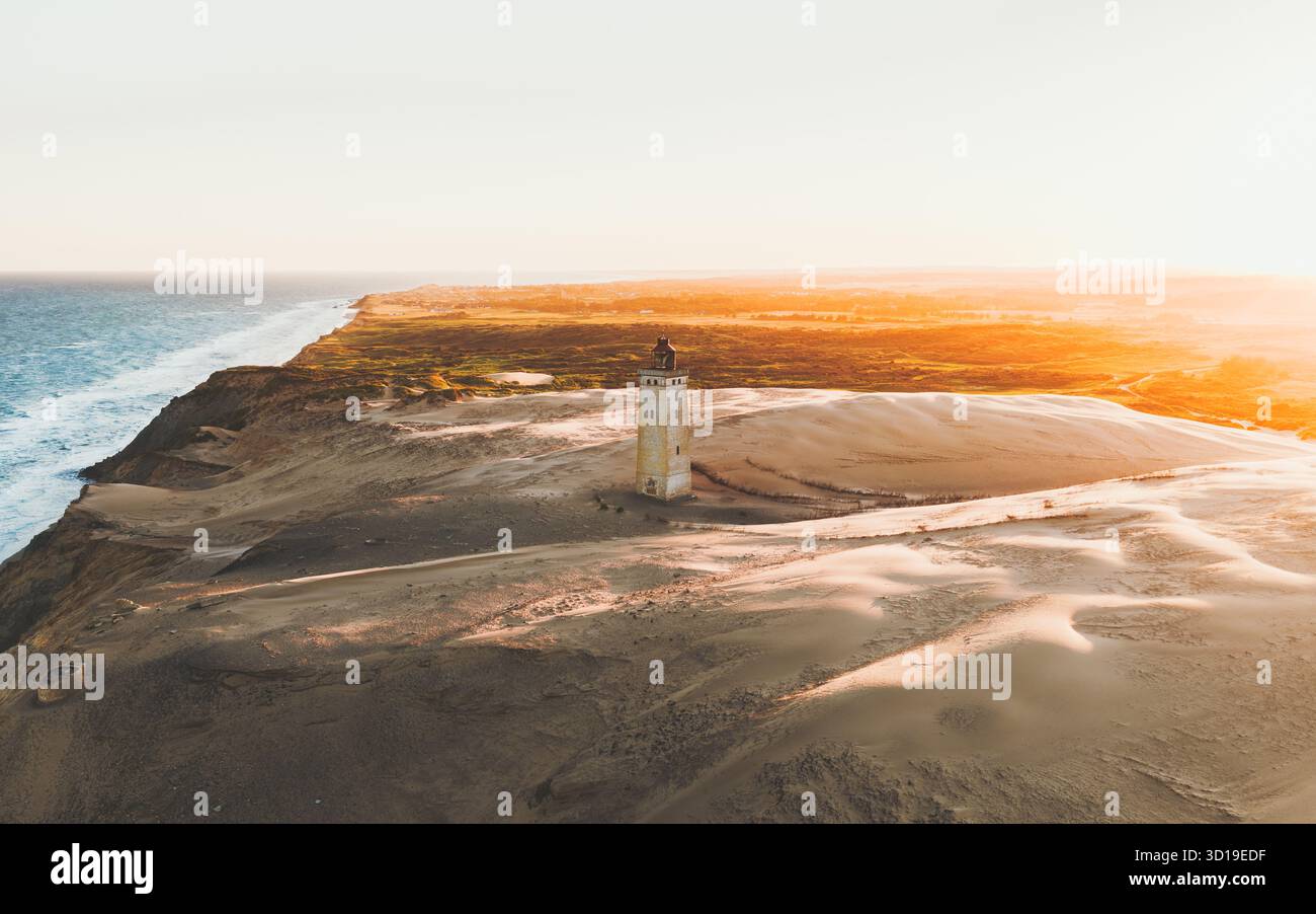 Aus der Vogelperspektive des Rubjerg Knude Lighthouse, der trotzig gegen den sich wandelnden Sand steht, mit der blauen Umarmung der Nordsee im Kontrast zu den goldenen Dünen, Rubjerg Knude, Dänemark. Stockfoto