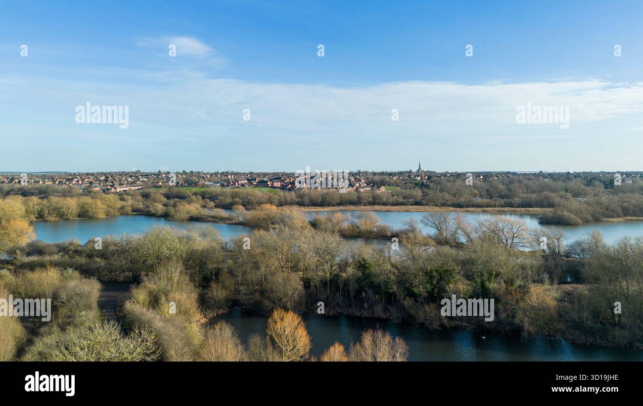 Aus der Vogelperspektive über Irthlingborough Lakes and Meadows in den Nene Wetlands, Northamptonshire, mit Higham Ferrers in der Ferne. Stockfoto
