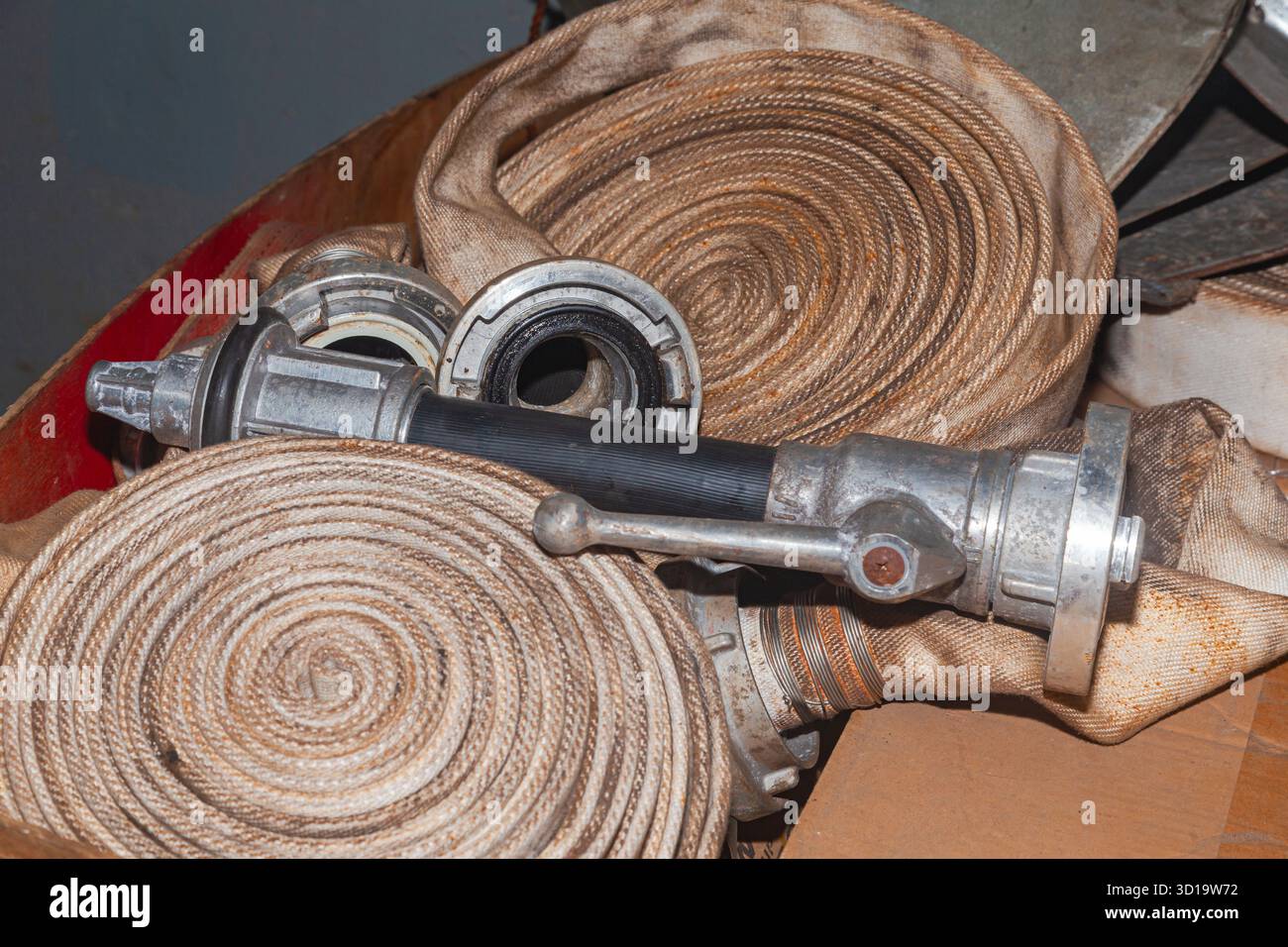 Verdrehte alte Löschschläuche mit Anschlüssen und Düsen Stockfoto