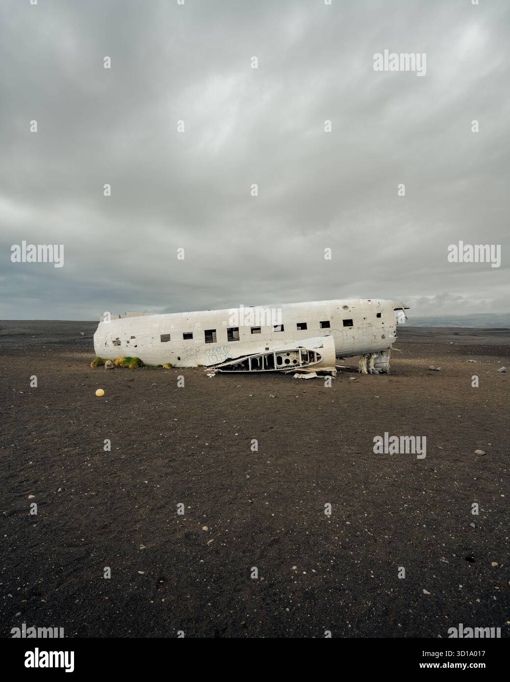 Der Blick auf die schroffe weiße Schale eines abgestürzten DC-3 steht im Kontrast zum riesigen, einsamen schwarzen Sandstrand unter einem glühenden Himmel, Sólheimasandur, Mýrdalshre Stockfoto