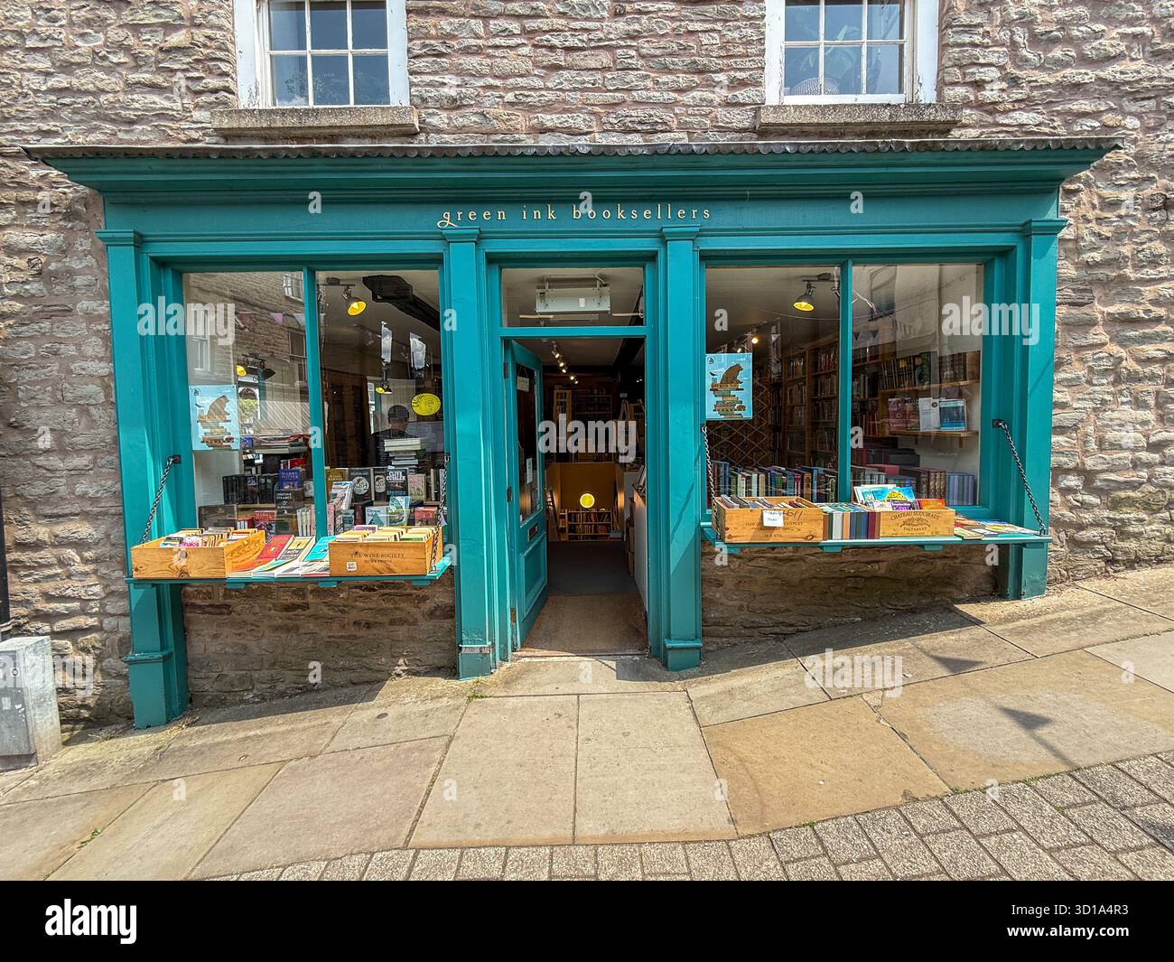 Der Blick auf die Green Ink Booksellers mit seiner einladenden türkisfarbenen Fassade lockt Buchliebhaber in der charmanten Steinarchitektur Hay-on-Wye, Wales, Stockfoto