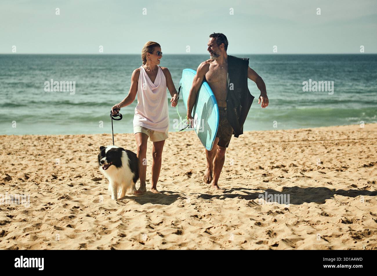 Machen Sie einen Spaziergang am Meer mit Surfboard and Dog Summer Walk: Paare, Collie, and the Ocean Love, Waves, and a Border Collie Coastal Morning: Surfboard in Stockfoto