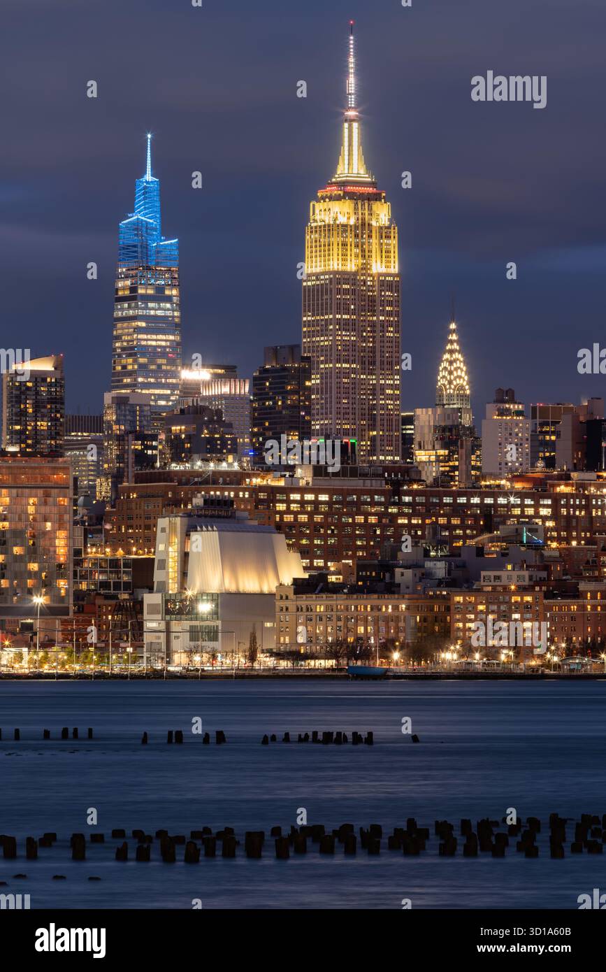 Blick auf New York bei Nacht vom Hudson River in Midtown Manhattan mit beleuchtetem Empire State Building, einem Vanderbilt und Chrysler Building Wolkenkratzern Stockfoto