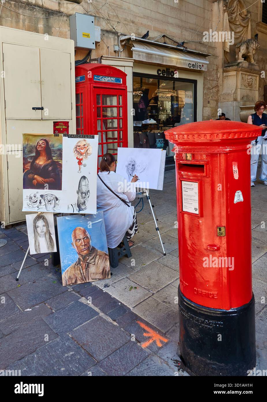 Outdoor Street Artist mit Karikaturen in der Nähe von Red Postbox, Red Phone Box und Shopfront an der historischen City Street in Valletta, Malta. Stockfoto