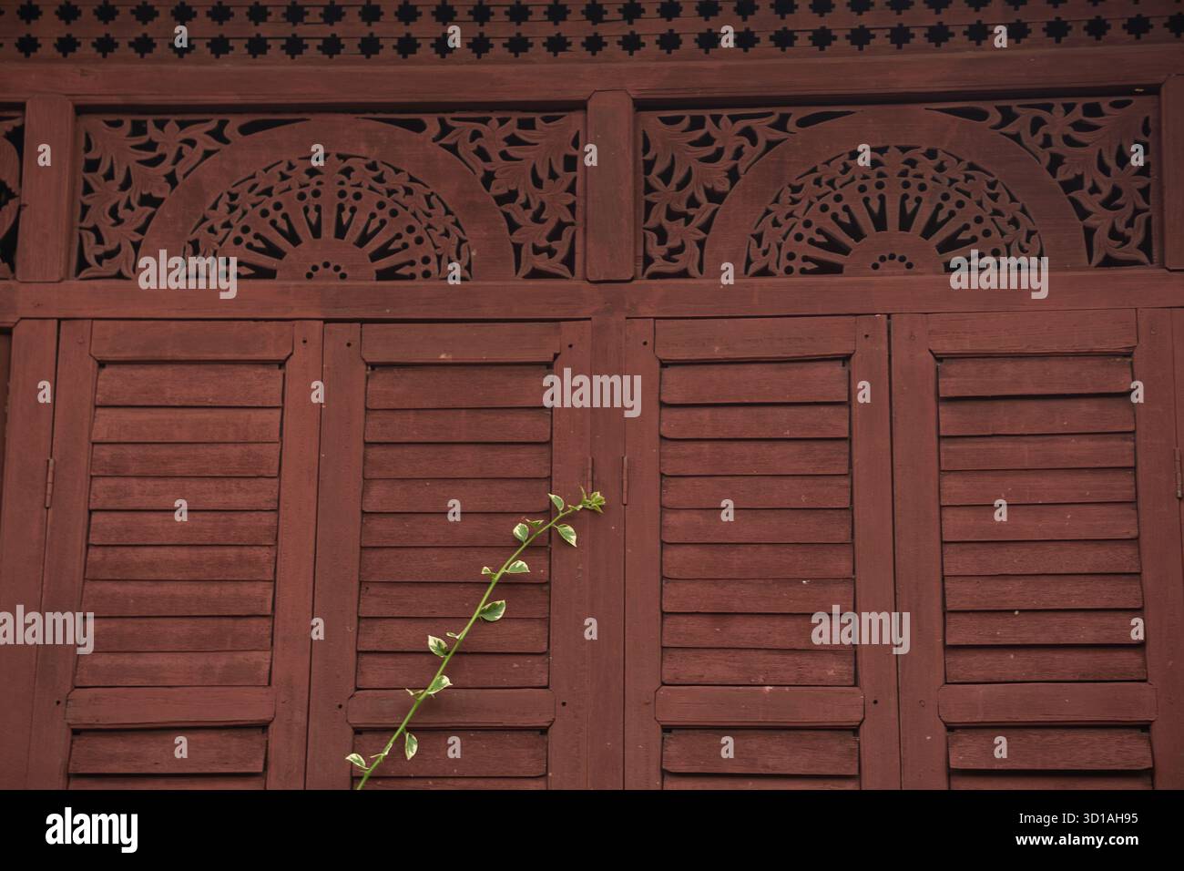 Traditionelle malaiische Holzläden mit geschnitzten Lüftungswänden, die komplexe Handwerkskunst und tropisches Architekturdesign in Malaysia zeigen Stockfoto