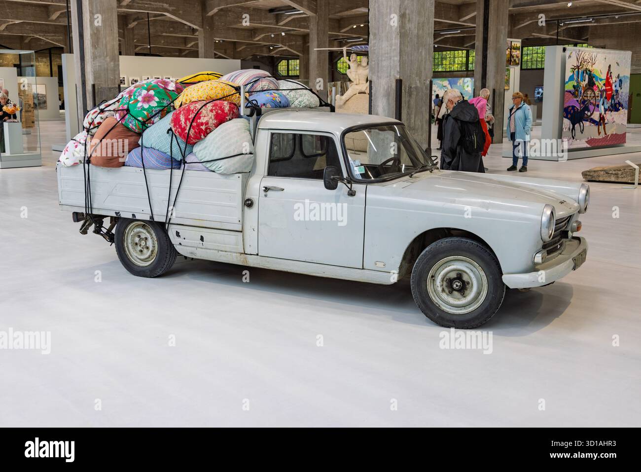 Ein alter Pickup-Truck, ein klassischer Peugeot 404, beladen mit bunten, gemusterten Decken und Kissen, als Ausstellung im Fenix Migration M ausgestellt Stockfoto