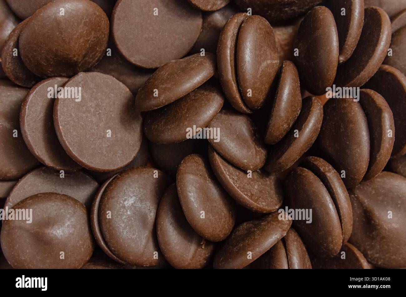 Eine detaillierte Nahaufnahme (Makro) eines Stapels von glatten, kräftigen braunen Schokoladenchips oder -Callets. Das Bild hebt die Textur und Form des in hervor Stockfoto