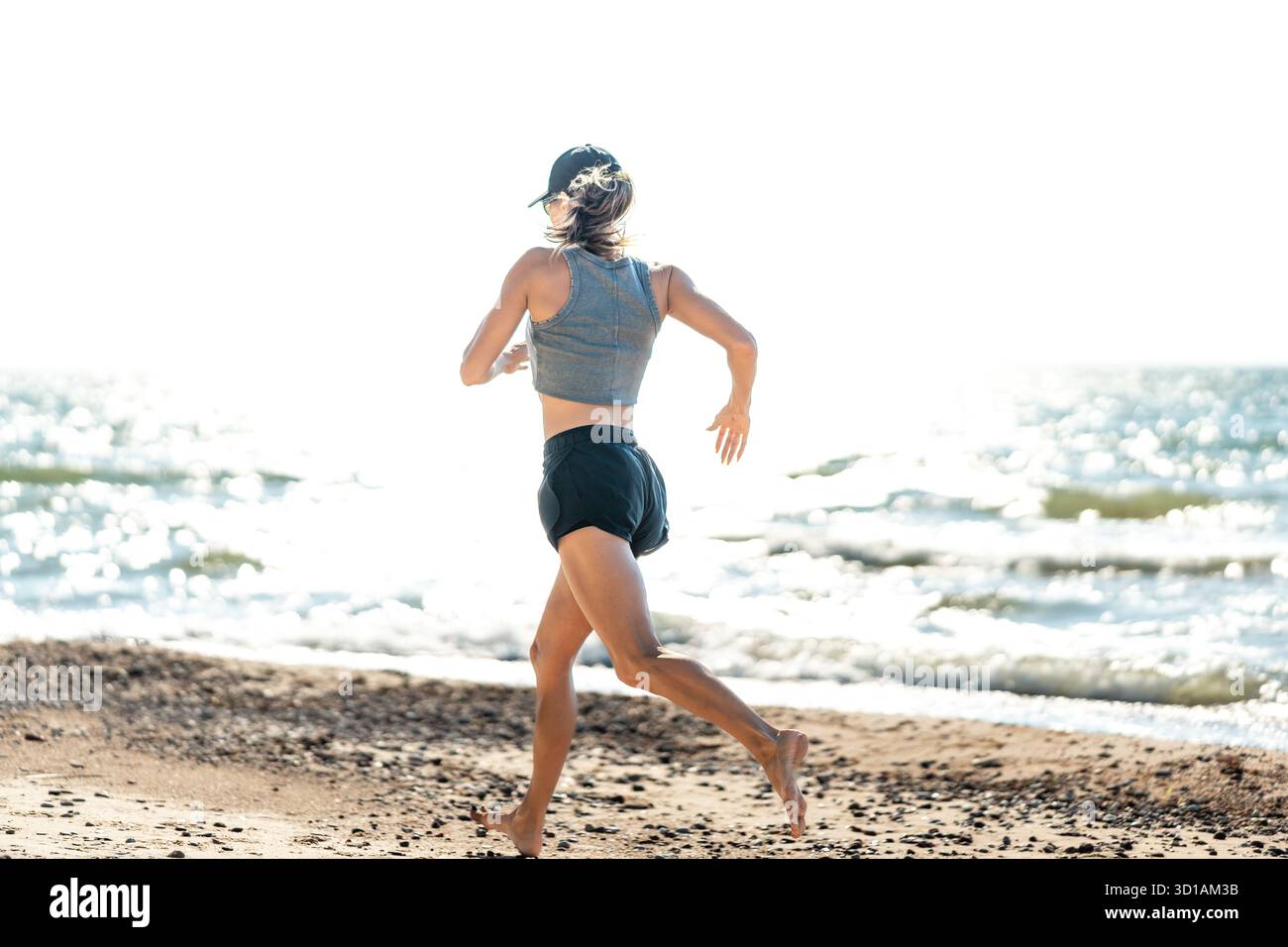 Die Dame bewegt sich ungehindert in Richtung entfernter Skyline, die Frau übt sich frei entlang der strahlenden Küstenlinie, die nach außen geht Stockfoto