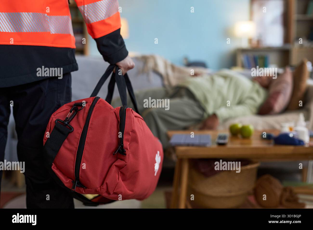 Ältere schwarze Frau, die bewusstlos auf dem Sofa liegt, während Notarztpraxis mit roter erste-Hilfe-Tasche in das Wohnzimmer eindringt und auf mögliche medizinische Notsituation reagiert Stockfoto