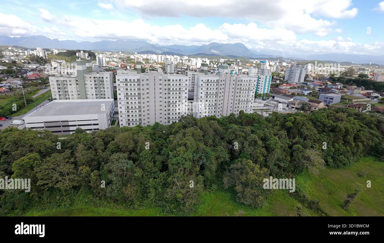 Blick aus der Vogelperspektive auf Wohngebäude, umgeben von Bäumen, mit Bergblick und blauem Himmel in Joinville, Brasilien. Stockfoto