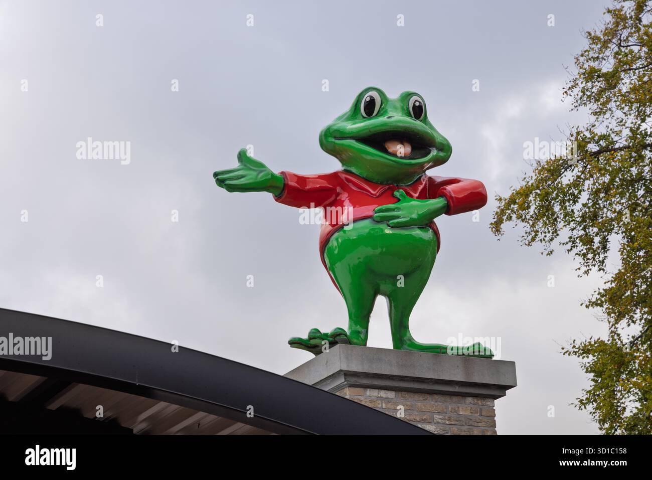 Eine große Statue von Rick dem Frosch, dem fröhlichen grün-roten Maskottchen von Duinrell, steht auf einem Sockel und begrüßt Besucher im beliebten Park. Wassenaa Stockfoto