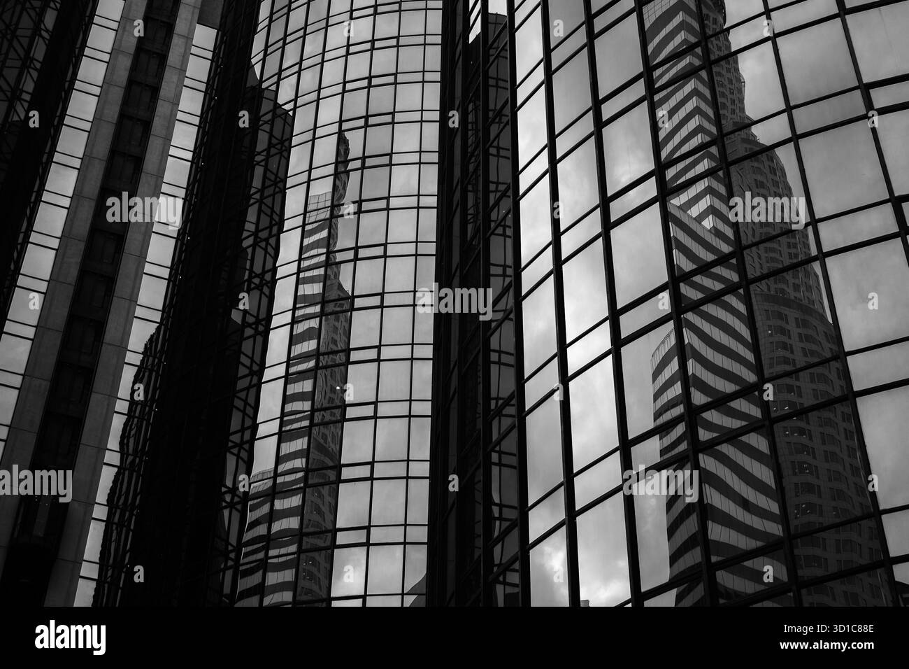 Glasfassaden-Reflektionen in Schwarz und weiß – abstrakte Architektur mit Symmetrie, Tiefe und moderner urbaner Geometrie Stockfoto