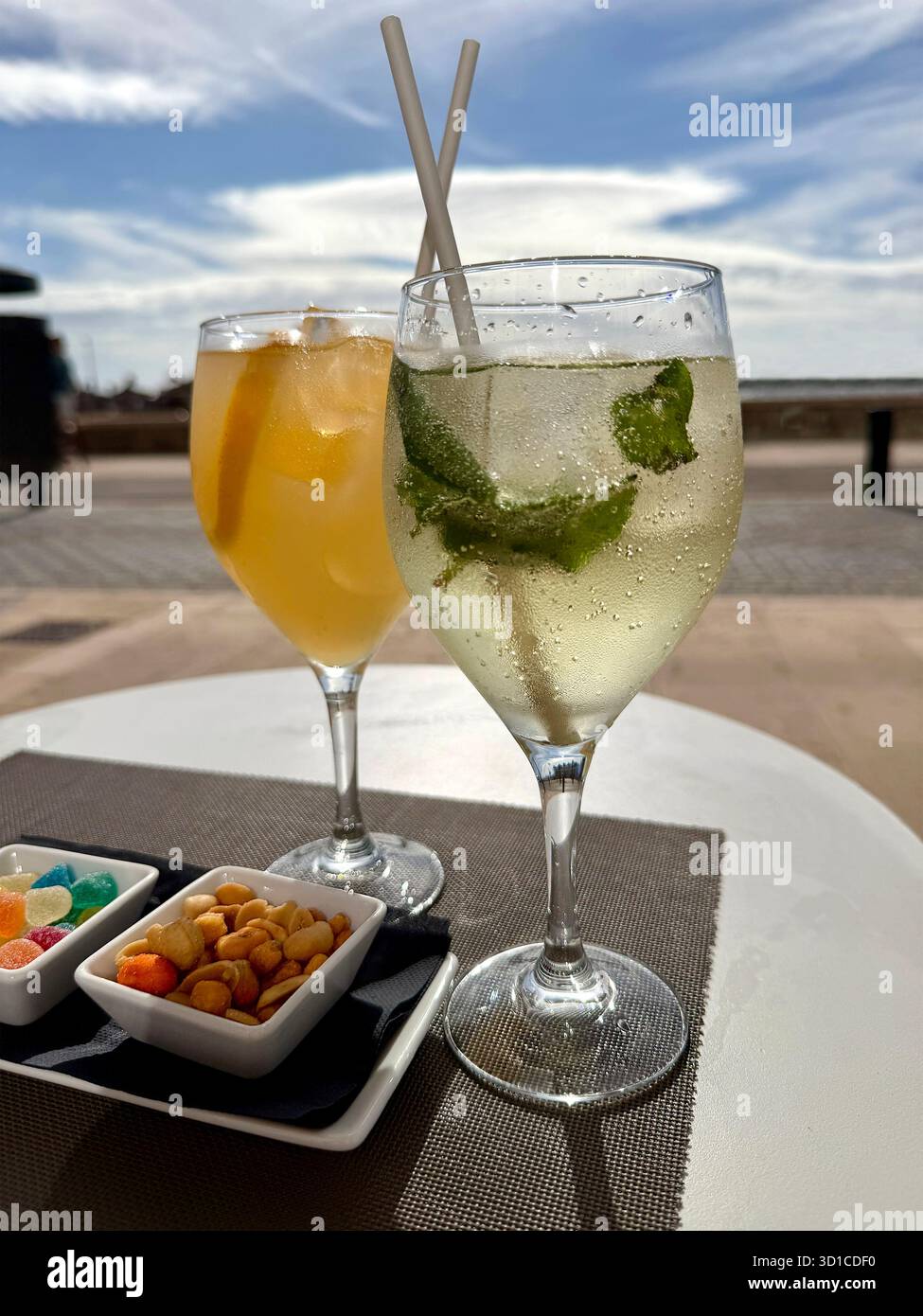 Nahaufnahme von zwei erfrischenden Cocktails, einem Mojito mit Snacks, serviert auf einem Tisch am Meer unter teilweise bewölktem Himmel Can pastilla mallorca - Smartphone-aufgenommenes Stockfoto