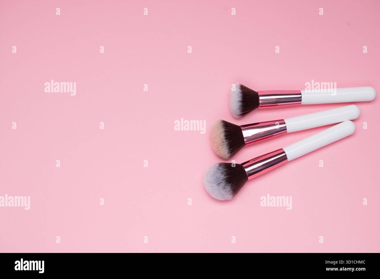 Drei Schminkpinsel, die ordentlich auf Einer rosafarbenen Oberfläche angeordnet sind Stockfoto