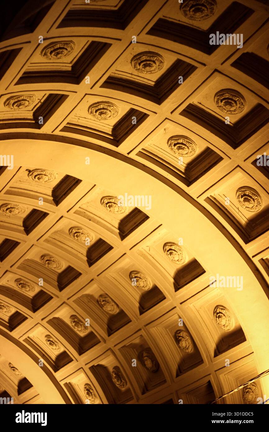 Dieses Foto fängt die Pracht der Bogendecken mit Reliefs ein, die von warmem, goldenem Licht beleuchtet werden, und verleiht dem ein Gefühl von Raffinesse und Hochmut Stockfoto