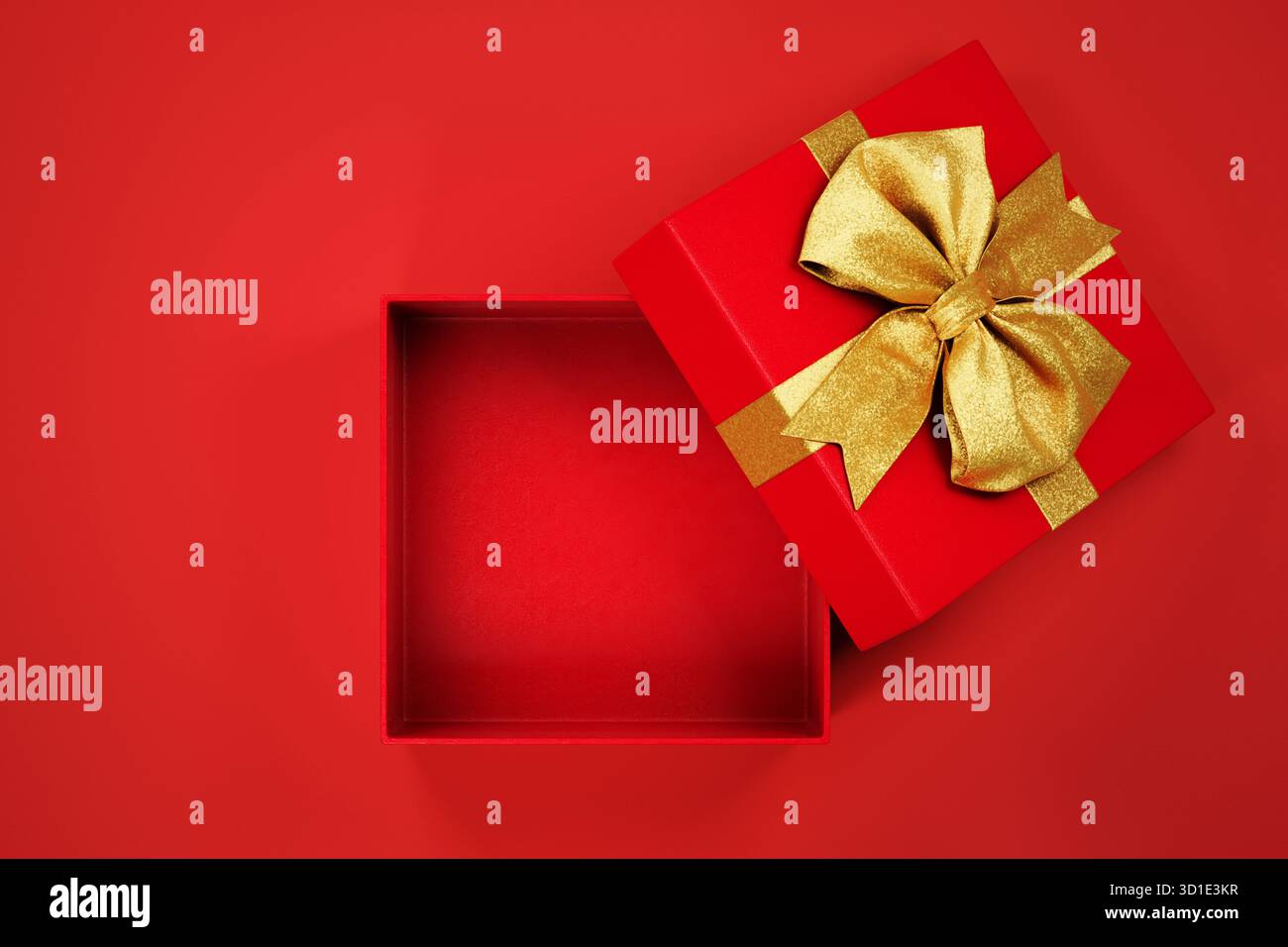 Offene weihnachts-Geschenkbox mit goldener Schleife auf rotem Hintergrund, Draufsicht. Neujahrsgeschenk mit Goldband-Mockup-Vorlage. Stockfoto