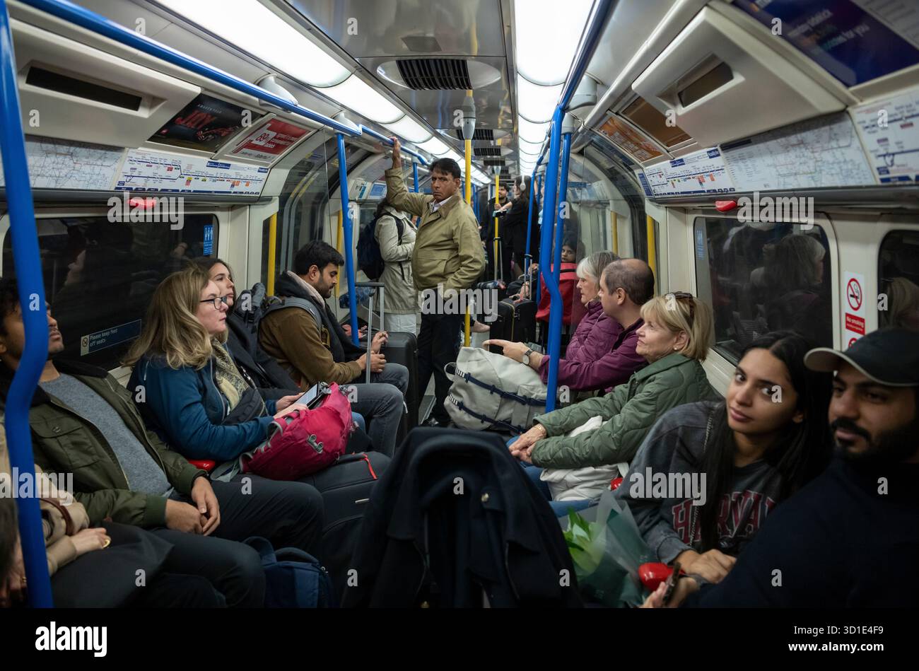 Passagiere der Londoner U-Bahn reisen mit ihrem Gepäck und Koffer in einem Kutscher der Piccadilly Line in Richtung Heathrow, Zentrum von London, England, Großbritannien Stockfoto