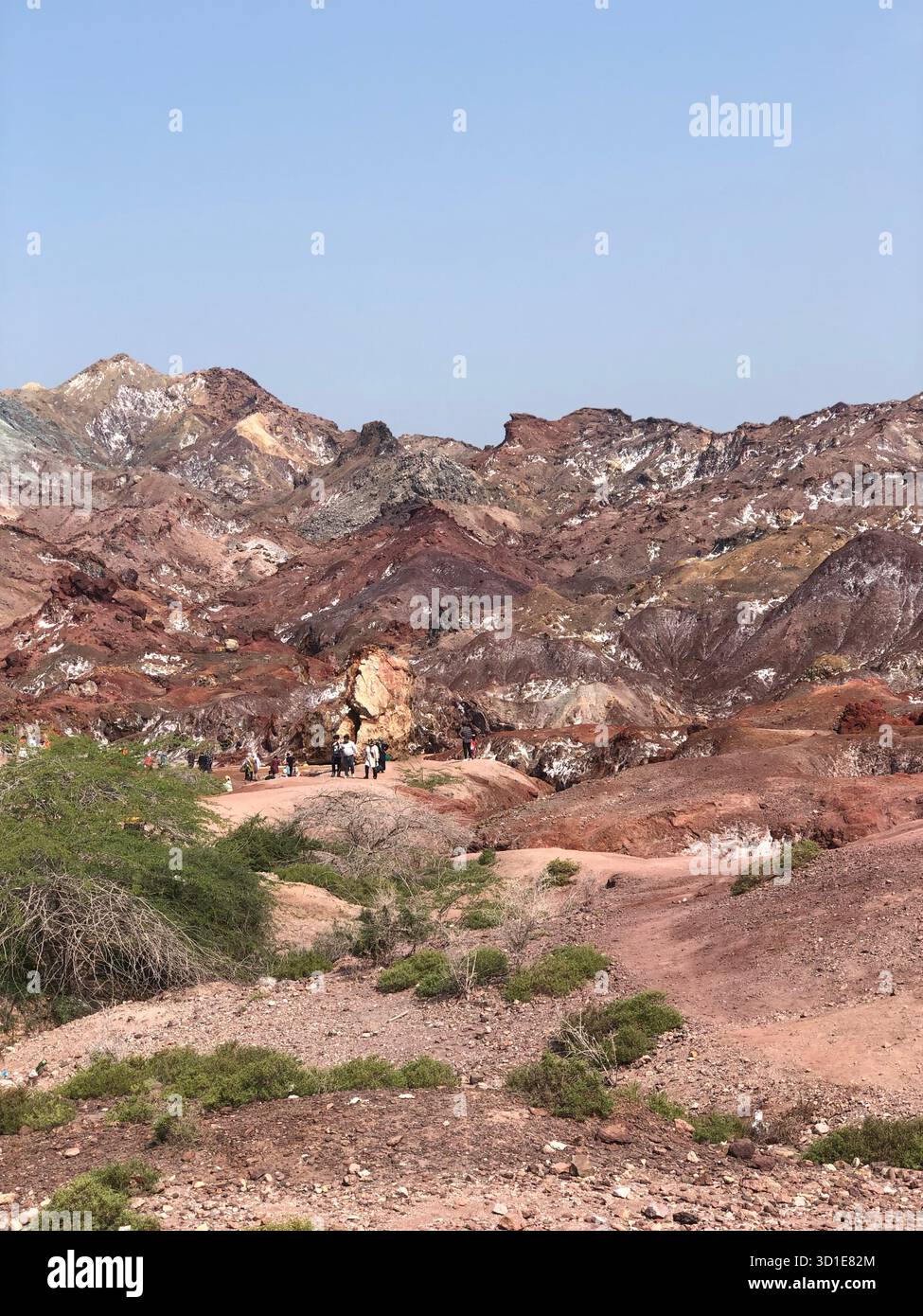 Besucher erkunden die farbenfrohen vulkanischen Berge der Insel Hormuz, Iran – eine surreale Landschaft, die von Naturmineralien gemalt ist. Stockfoto