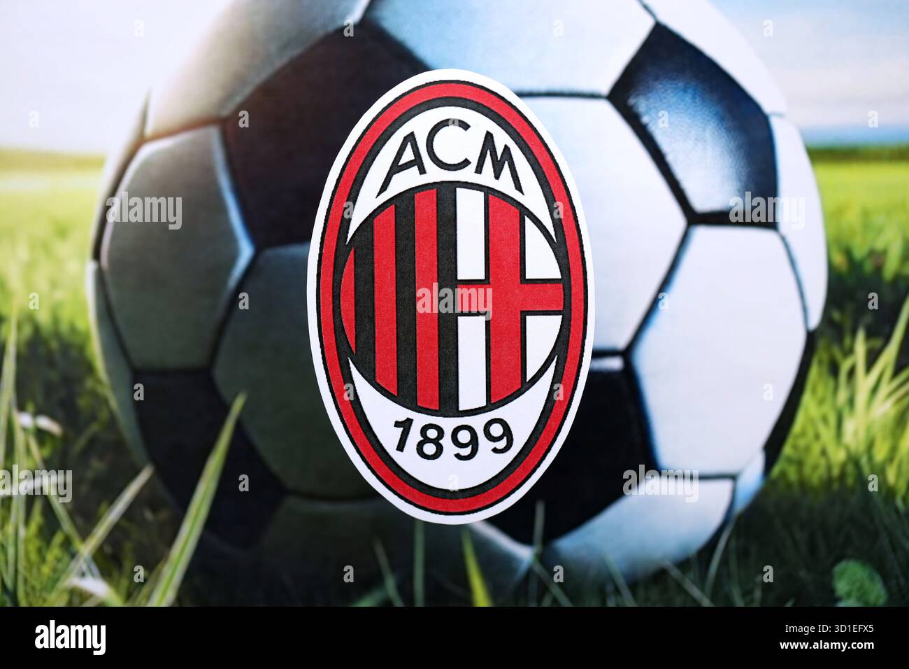 KIEW, UKRAINE - 23. FEBRUAR 2025 das Abzeichen des Fußballvereins AC Mailand liegt auf einem Fußballbanner im Hintergrund Stockfoto
