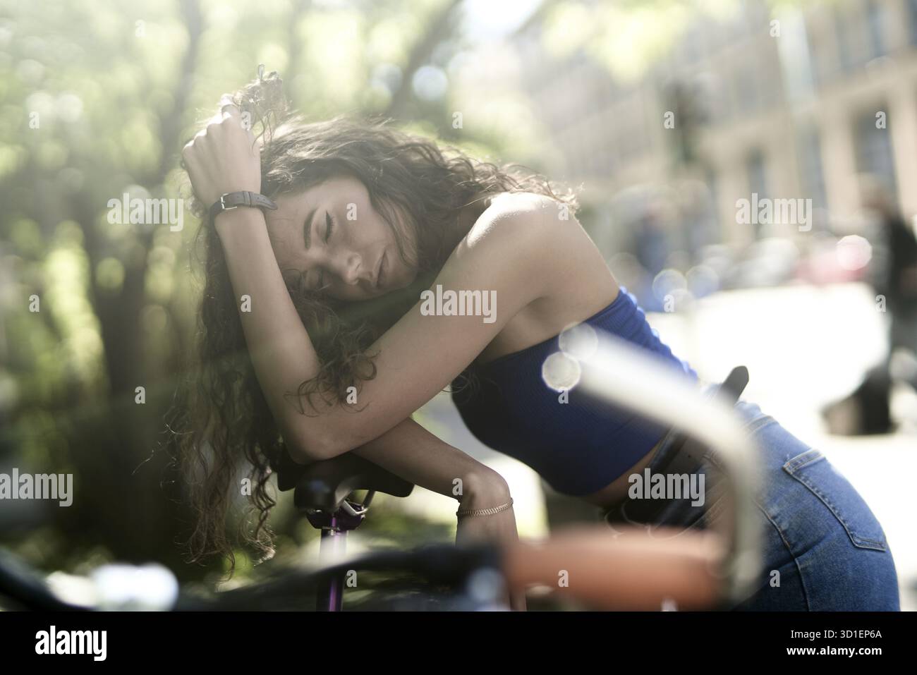WEHMÜTIGES NICKERCHEN in der Stadt mit dem Fahrrad, kurze Pause auf dem Weg zur oder von der Arbeit oder Universität, Alltag, Zeit nehmen, wehmütig erschöpft Stockfoto