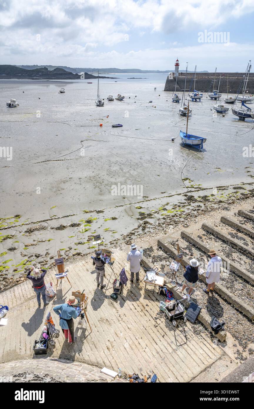 Eine Gruppe von Plein-Air-Amateur-Malern und Künstlern steht mit Staffeleien auf einer Betonrampe und schaut auf den großen, schlammigen Sandstrand, auf dem Numero steht Stockfoto