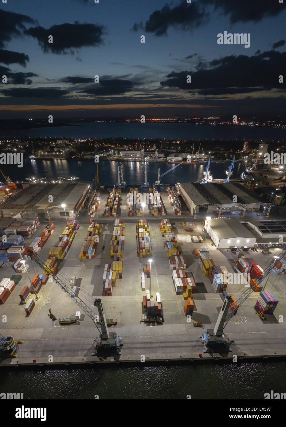 Beleuchteter Hafen bei Nacht mit Containern und Kränen, von oben gesehen vom Wasser. Aus der Vogelperspektive zu einem Container-Entladeterminal des Hafens von Burgas, BU Stockfoto