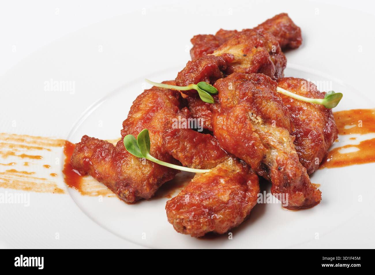 Gebratene Hähnchenschenkel in roter, scharfer Karamellsauce mit grünen Bohnensprossen auf weißem Teller Stockfoto