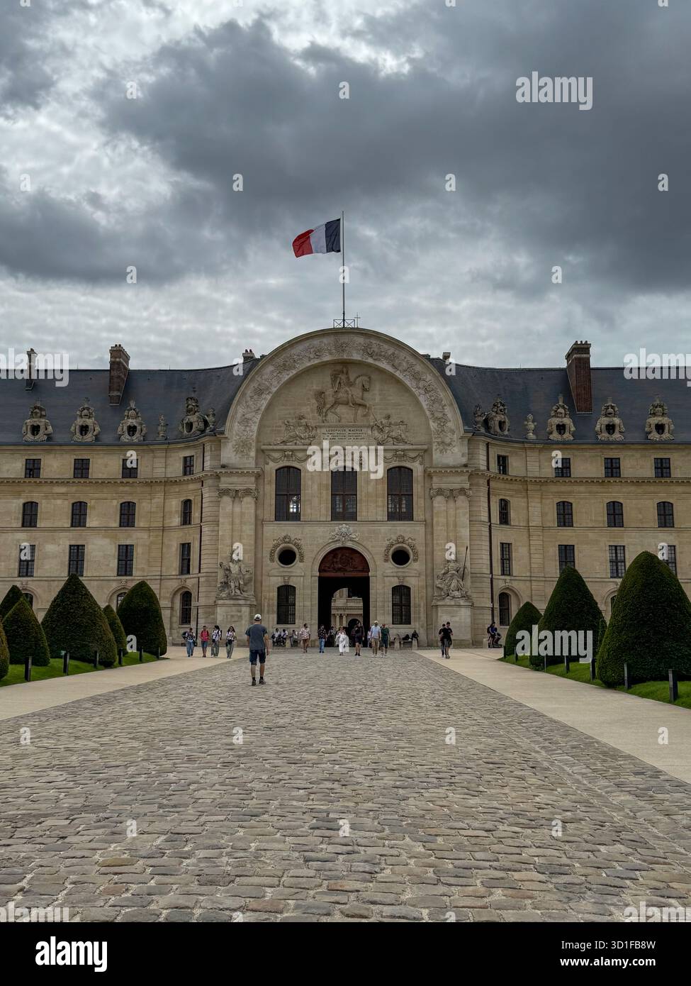 Besucher gehen in Richtung des Haupteingangs des invalides in paris, frankreich, unter einem dramatischen bewölkten Himmel. - Smartphone-aufgenommenes Stockfoto