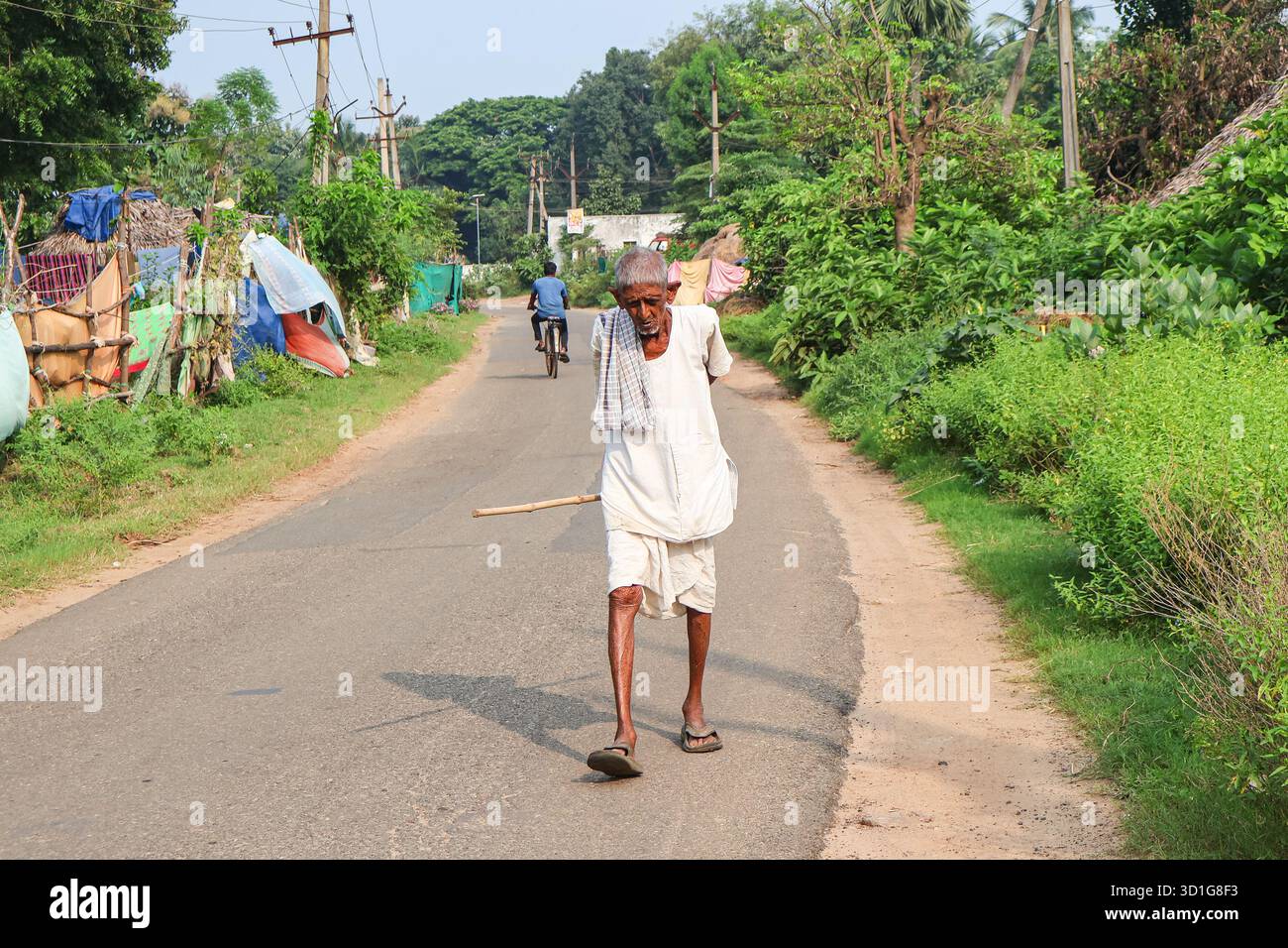 Bheemili, Visakhapatnam, Andhrapradesh - 10. September 2025: Ein alter Mann, der auf einer Dorfstraße läuft und einen Stock in der Hand hält. Alter indischer Mann. Stockfoto