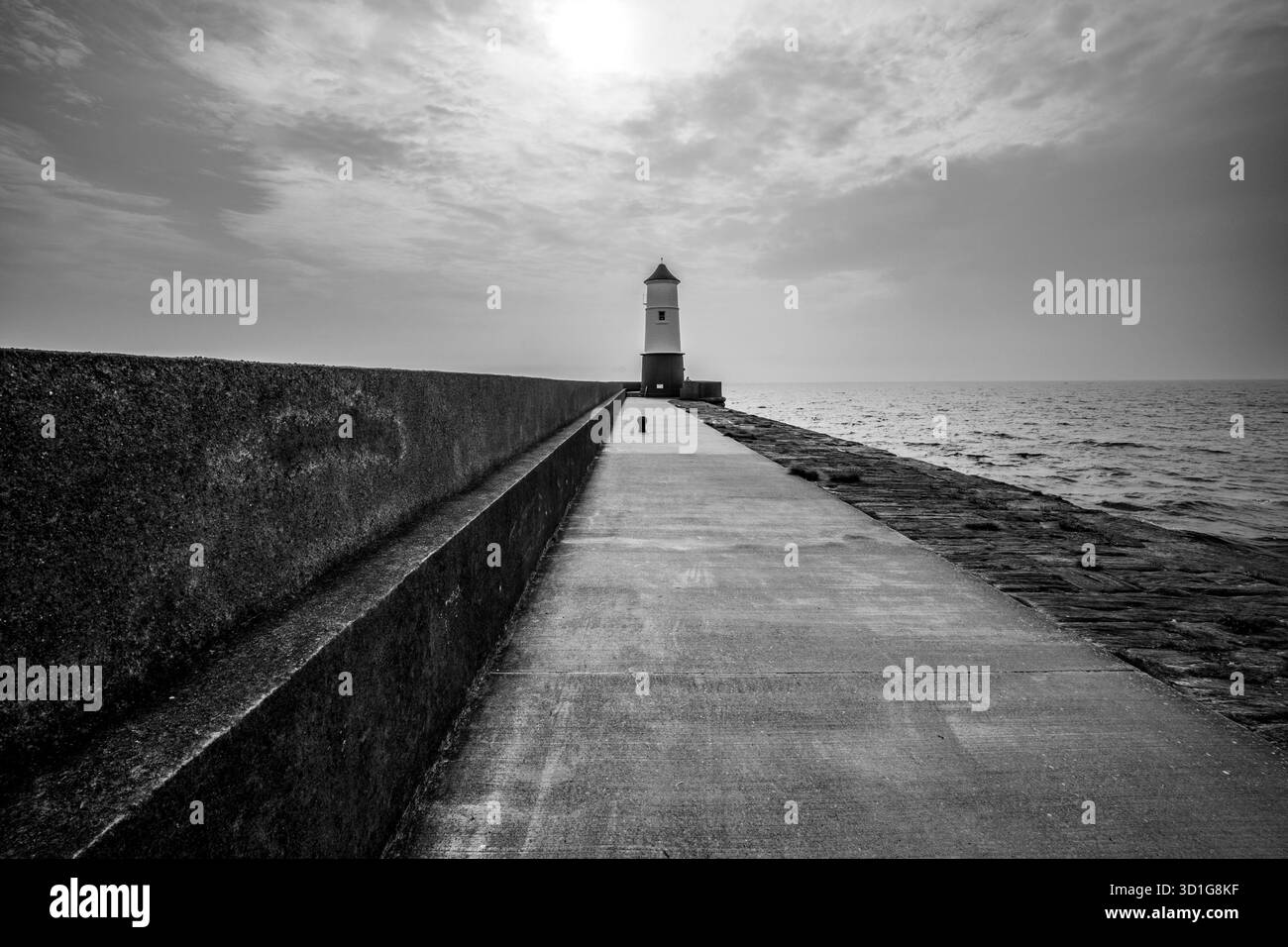 Schwarzweißbild des Leuchtturms am Pier bei Berwick upon Tweed, gesehen entlang der Betonmauer und des Gehwegs Stockfoto