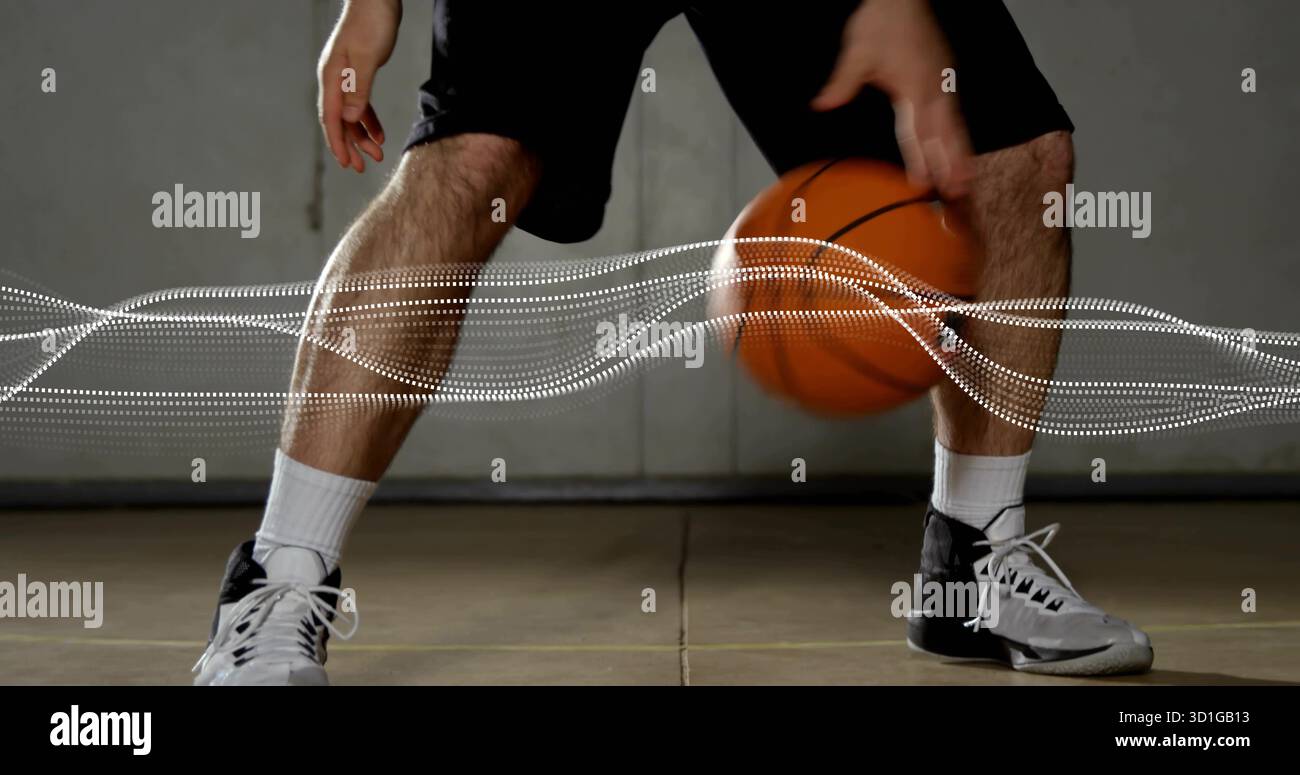 Athleten dribbeln Basketball im Fitnessstudio mit Crew-Socken, Basketballschuhen und weißem Wellenüberzug Stockfoto