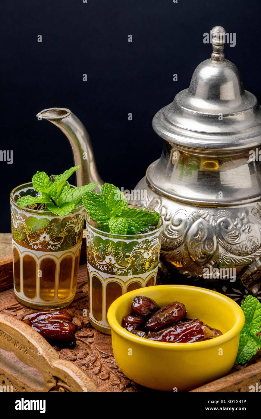 Teekanne und Teegläser mit Minze und Schüssel mit Datteln Stockfoto