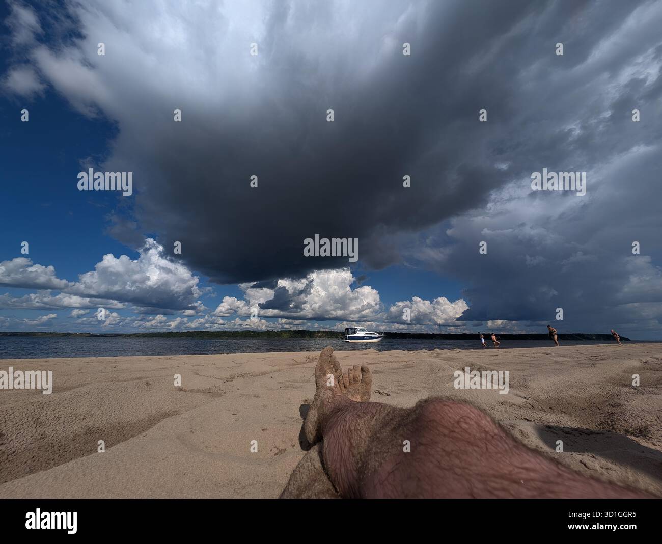 Ein ruhiger Blick auf den Strand mit sandigem Ufer und dramatischen Wolken, die sich über dem Himmel sammeln, perfekt für Entspannung oder Naturprojekte. Stockfoto