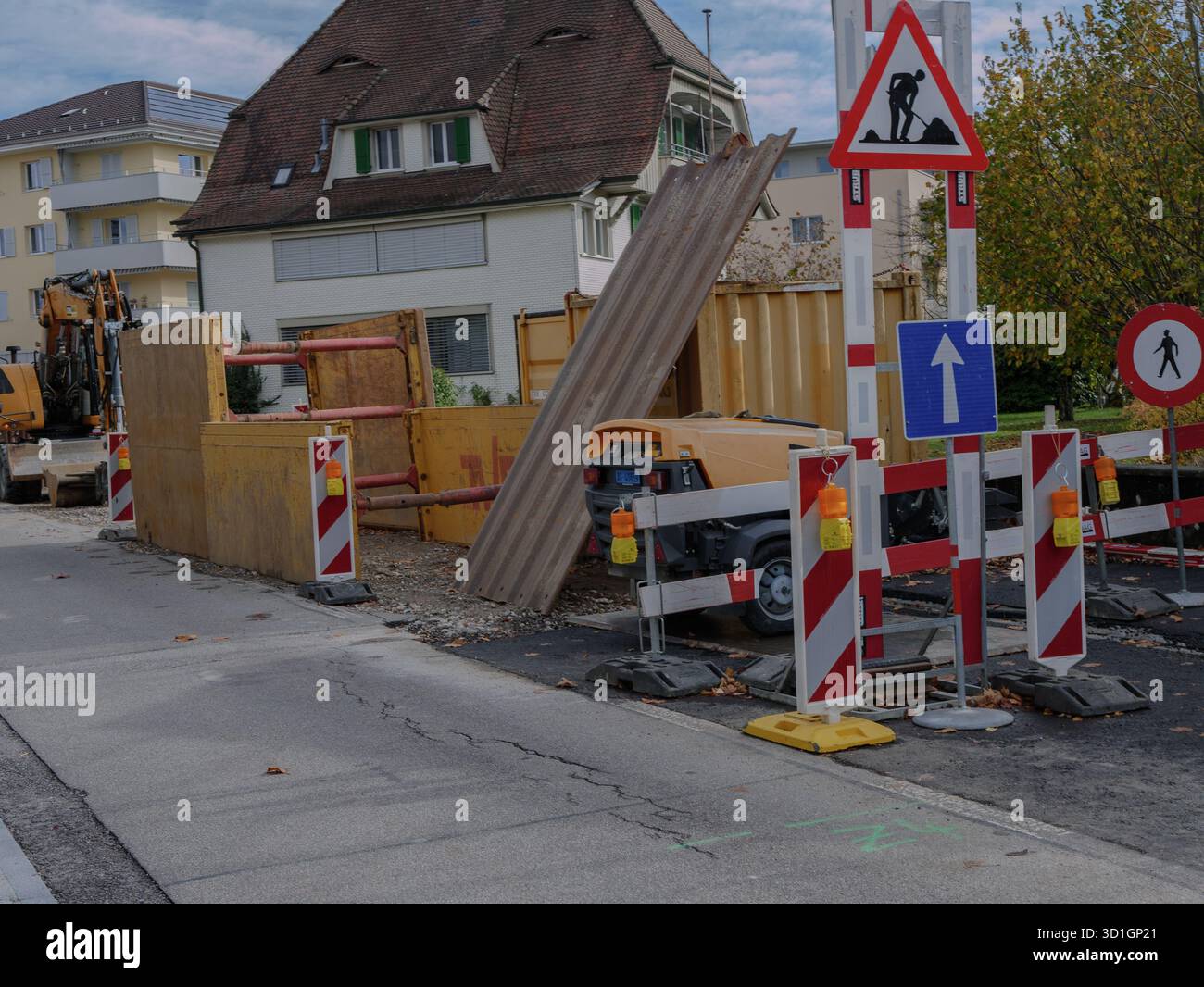 Städtischer Straßenbau mit Bagger, Sicherheitsbarrieren und Verkehrswarnschildern bei Straßeninstandhaltung und Instandsetzung der Infrastruktur. Profi-Foto. Stockfoto