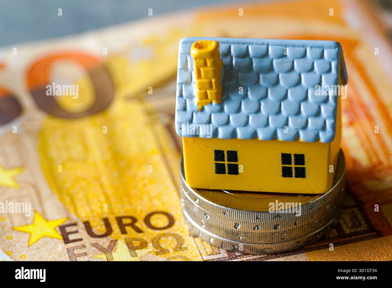 Miniaturhaus auf Euro-Münzen und 50 Euro-Banknoten als Symbol für Hypotheken- und Immobilienfinanzierung Stockfoto