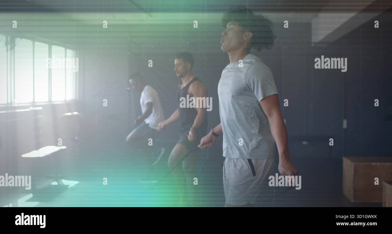 Drei Männer, die Sprungseile im Fitnessstudio überspringen, mit großen Fenstern, Plyboxen, Hantelbank Stockfoto
