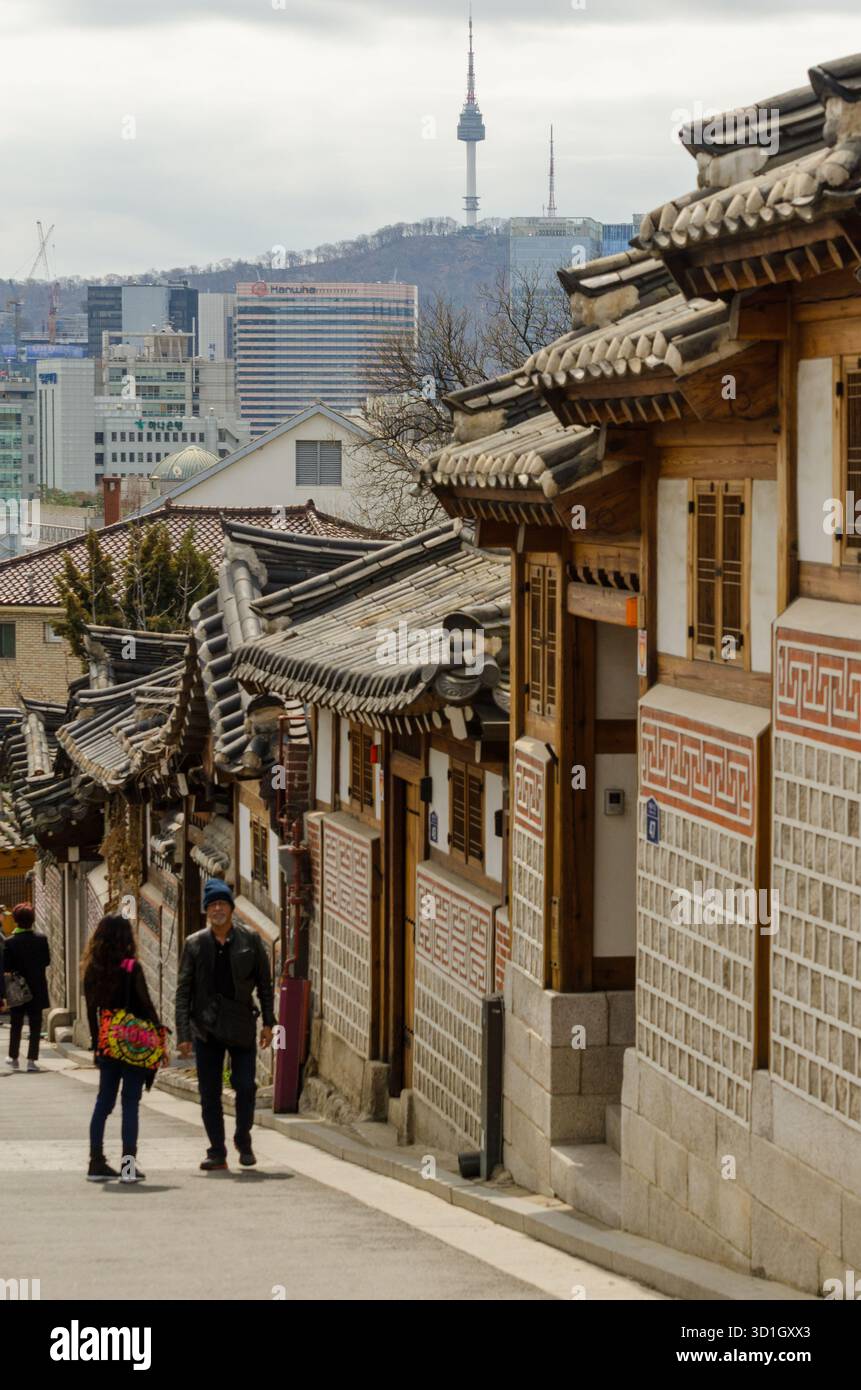 Seoul, Gyeonggi, Südkorea. 31. März 2015: Touristen erkunden das traditionelle hanok-Dorf in Seoul mit dem Namsan Seoul Tower im Hintergrund. Stockfoto