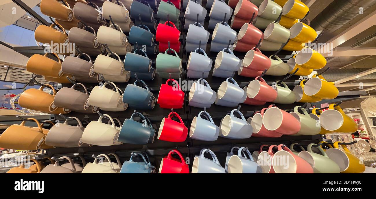 Farbenfrohe Keramikbecher sind in einem optisch ansprechenden Display angeordnet, das verschiedene Farbtöne und Designs präsentiert und perfekt für den Einzelhandel geeignet ist. - Smartphone-aufgenommenes Stockfoto