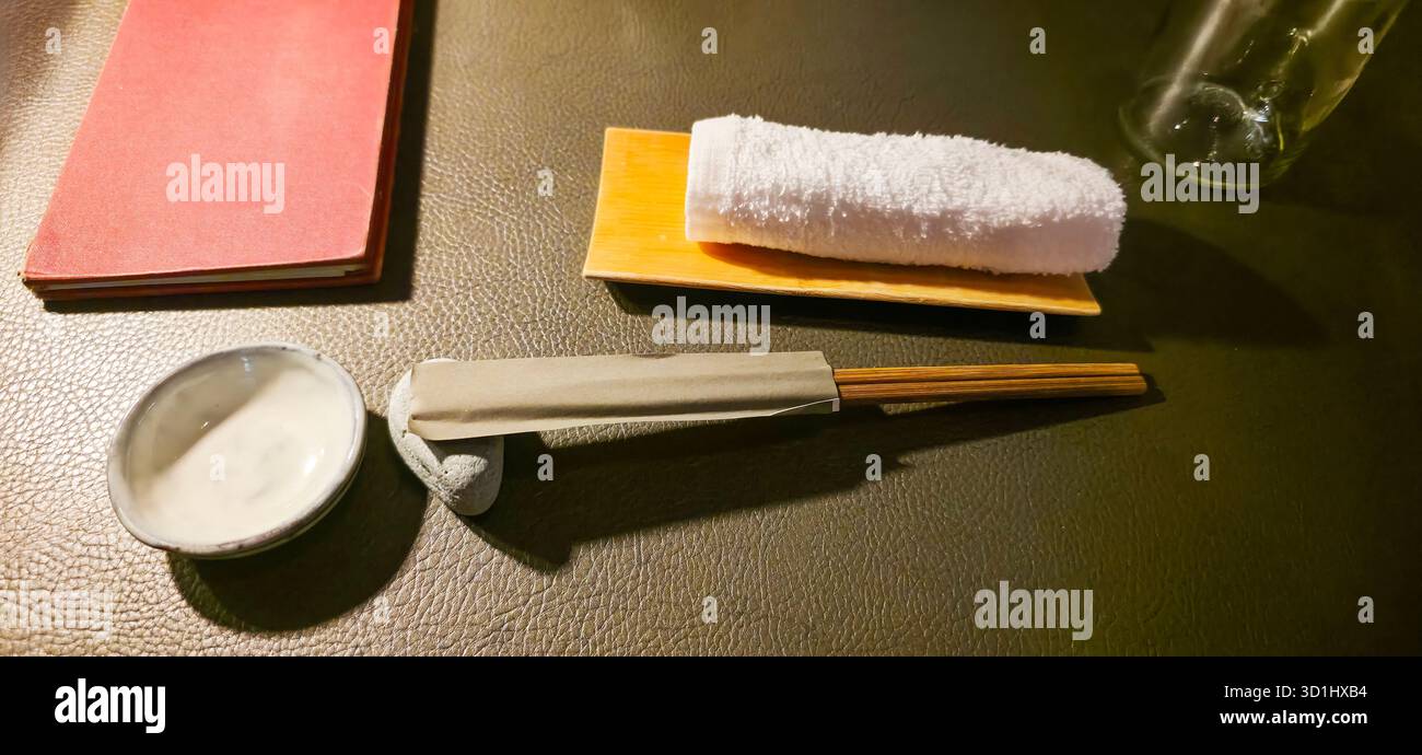 Die elegante Essensanlage umfasst Essstäbchen, Handtücher und Soßen auf Holztisch. - Smartphone-aufgenommenes Stockfoto