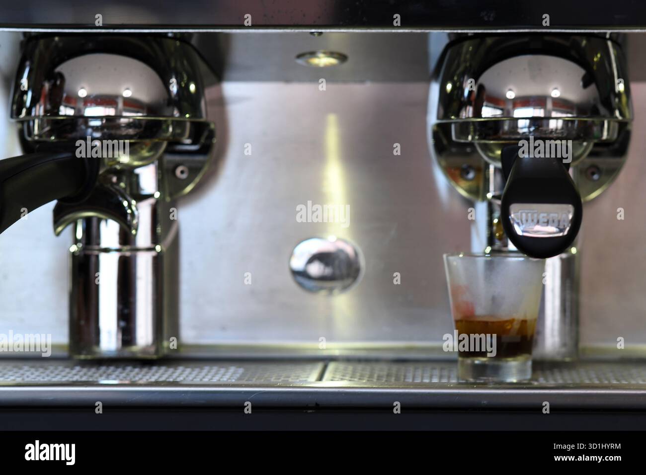 Cremona, Italien - 21. Juli 2025 Nahaufnahme von Barista, der Espresso Shot in transparenter Tasse aus einer professionellen Kaffeemaschine mit Chromfinish und zubereitet Stockfoto
